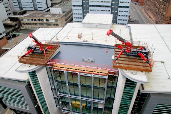 UNIC URW-706 Mini Spider Cranes performing a tandem lift on a rooftop.
