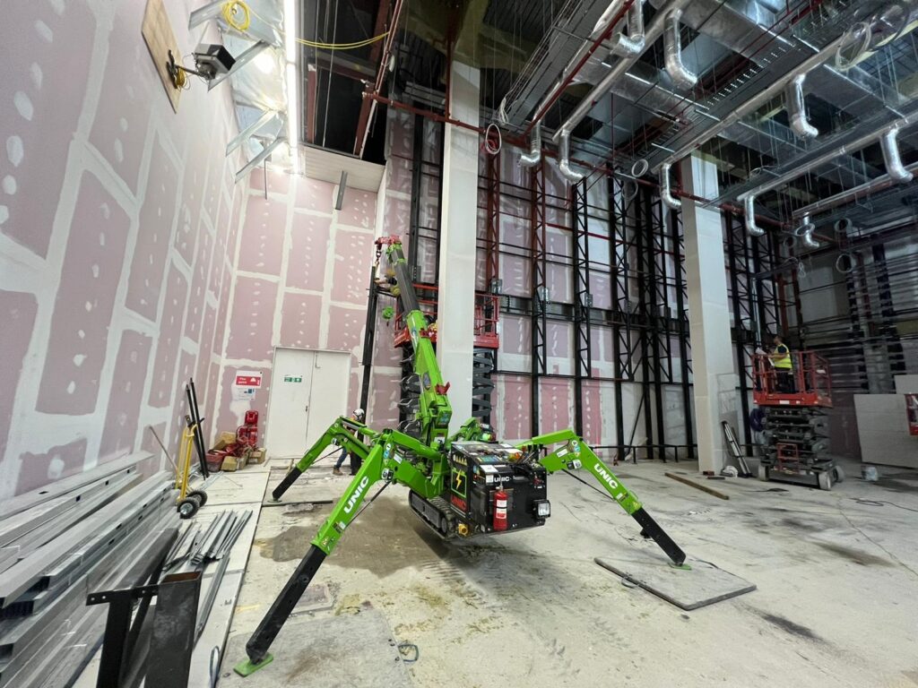 The UNIC Tracked ECO-295 Mini Spider Crane lifting steel beams inside a first-floor store in Westfield London shopping centre.