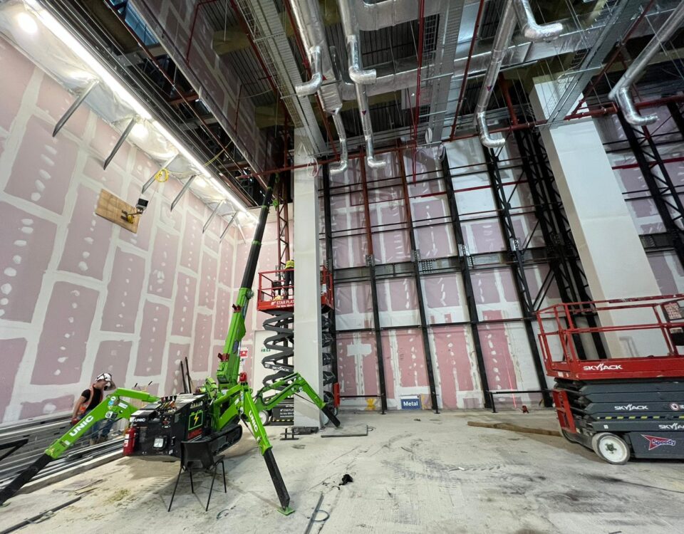 The UNIC Tracked ECO-295 Mini Spider Crane lifting steel beams inside a first-floor store in Westfield London shopping centre.