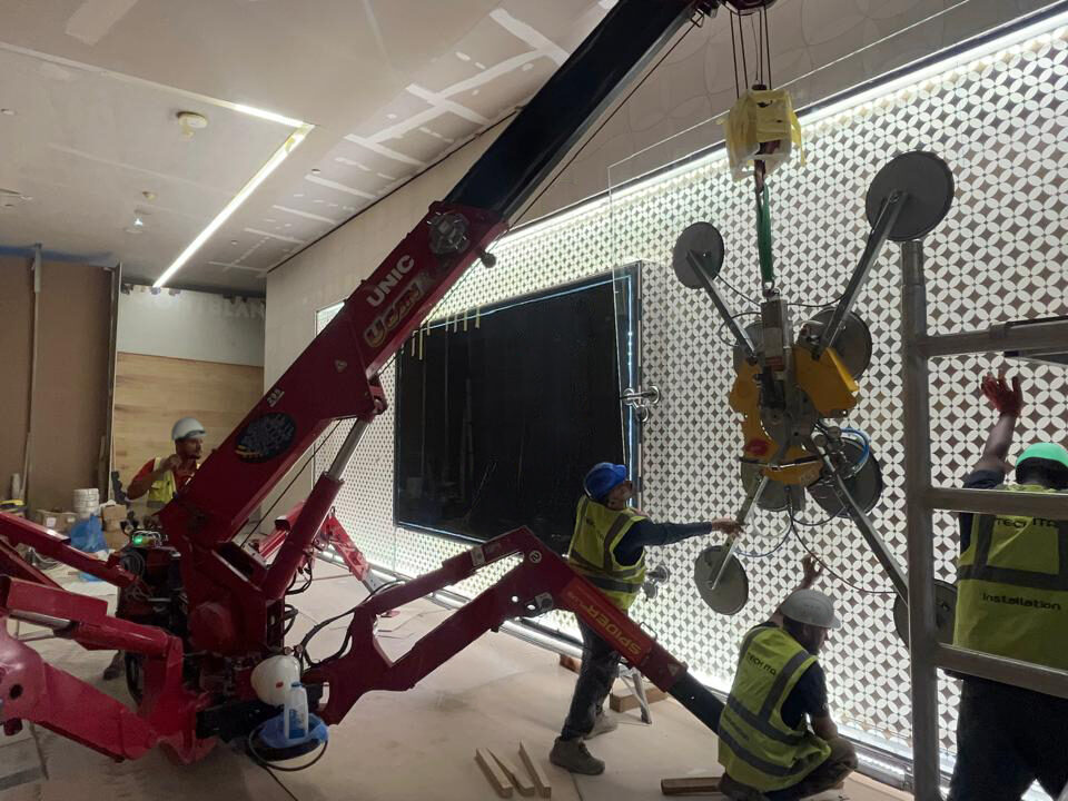 A UNIC URW-295 Mini Spider Crane installing oversized glazing inside Solitaire Mall.