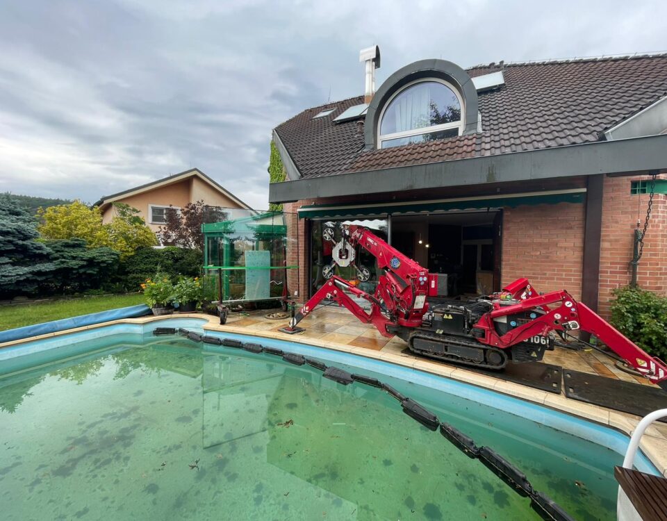 The UNIC URW-095 Mini Spider Crane installing glazing next to a pool for a family home.